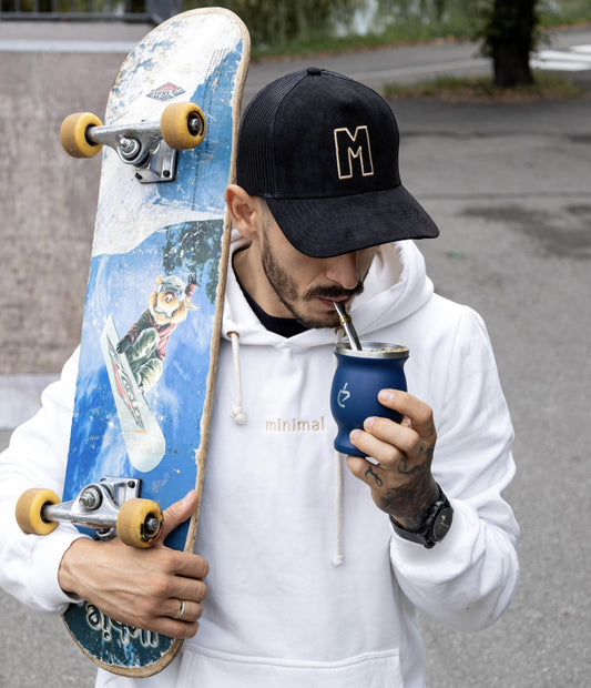 Homme tenant un skate et une calebasse bleue en main
