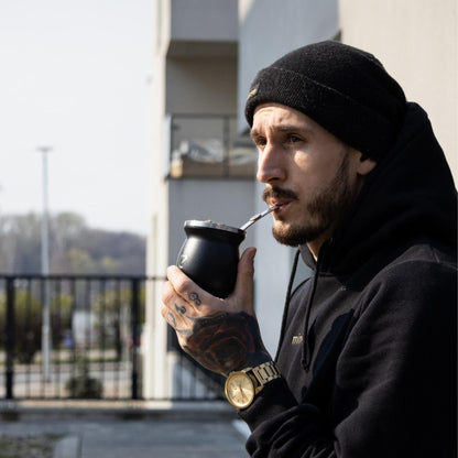 Homme vêtu de noir buvant à la calebasse noire